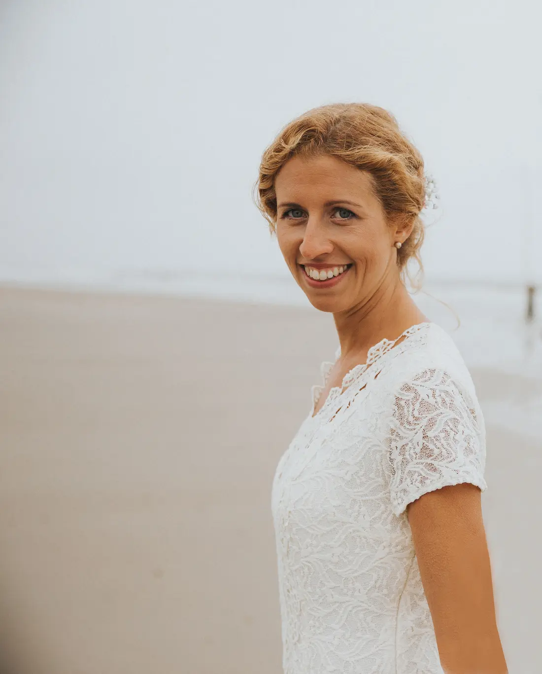 Angelika Isabelle Fritsch-Marko lächelt, im Hintergrund der neblige Strand